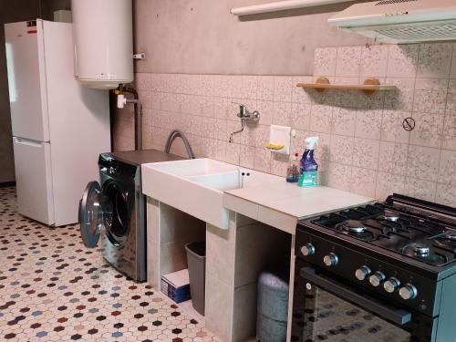 une cuisine avec un évier et une cuisinière dans l'établissement Maison calme proche plage, jardin, wifi, animaux sur demande - FR-1-306-1290, à Mesquer