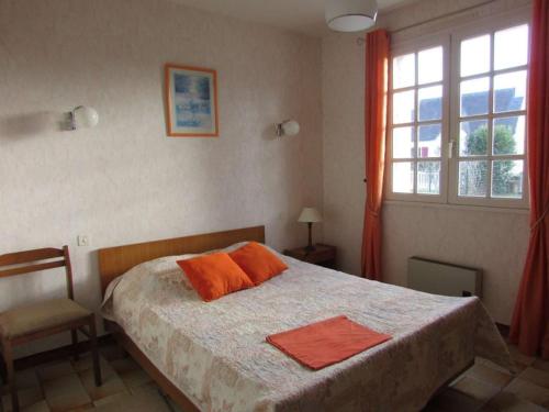 une chambre avec un lit avec des oreillers orange et une fenêtre dans l'établissement Maison 5 pièces calme proche plage avec jardin, animaux acceptés - FR-1-479-186, à Erdeven