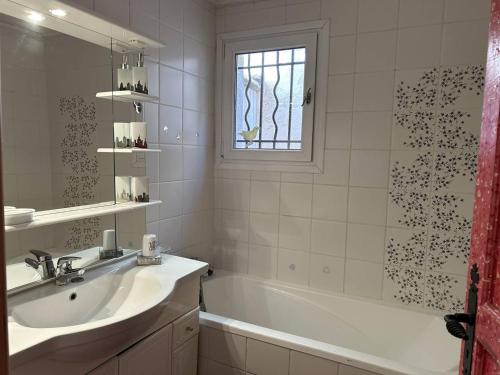 La salle de bains est pourvue d'un lavabo, d'une baignoire et d'une fenêtre. dans l'établissement Villa 5 pièces avec piscine privée près de la plage au Lavandou - FR-1-251-852, au Lavandou