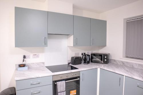 a white kitchen with white cabinets and a microwave at Newcastle Upon Tyne View Haven in Newcastle upon Tyne