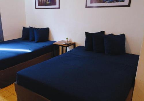 two beds in a room with blue sheets and a table at Depa Familiar a 2 cuadras del Auditorio Benito Juárez in Veracruz