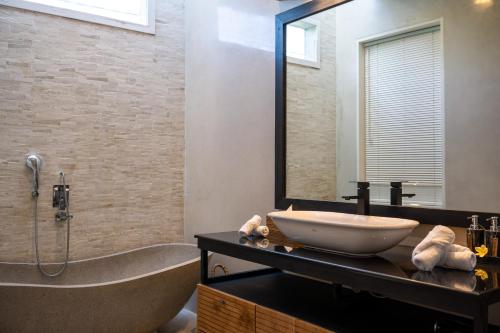 a bathroom with a sink and a tub and a mirror at Villa Sound Canggu in Mengwi