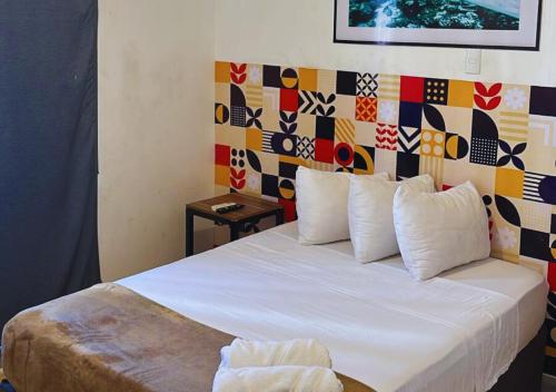 a bedroom with a white bed with a colorful wall at Depa a 3 min de Plaza Portales in Veracruz