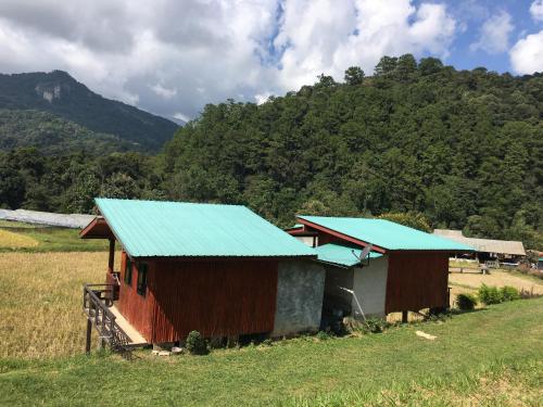 a barn with a blue roof in a field at Mukakee in Ban Sop Mae Klang