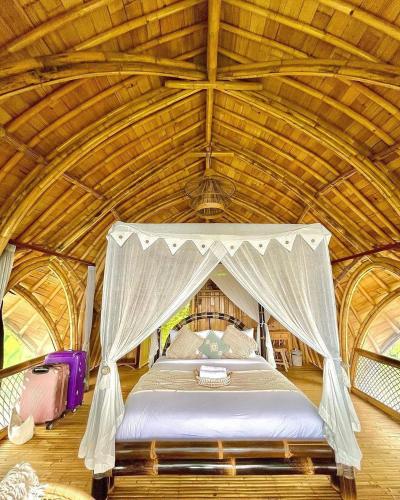 a bed in a room with a wooden ceiling at Laputa Bali in Sidemen