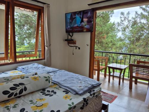 a bedroom with a bed and a balcony with a television at Villa 2Cemara in Batureo 1