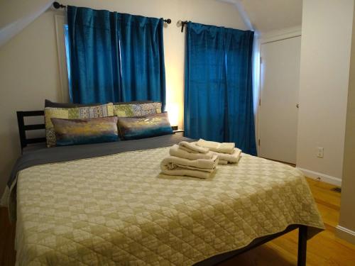 a bedroom with a bed with blue curtains and towels on it at Convenient 2 bed Apt in Everett a Short Walk to Encore in Everett