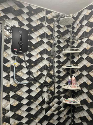 a bathroom with a black and white tiled wall at D' Alamanda HOMESTAY CHINI in Kampong Sakai