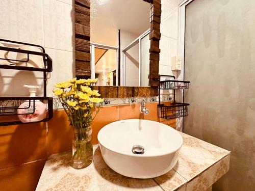 a bathroom with a sink and a vase with flowers at Dream Garden Villa Hotel Night Bazaar ChiangMai in Chiang Mai