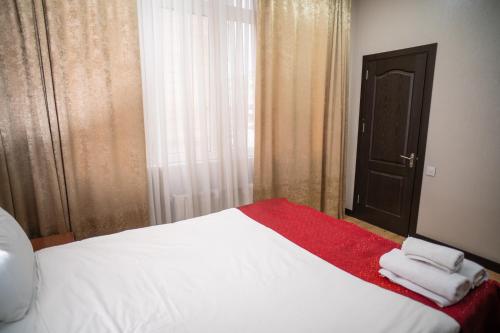 a bedroom with a large white bed with a red blanket at Consul Hotel in Baku