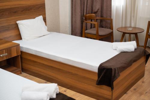 a bedroom with two beds with a chair and a table at Consul Hotel in Baku