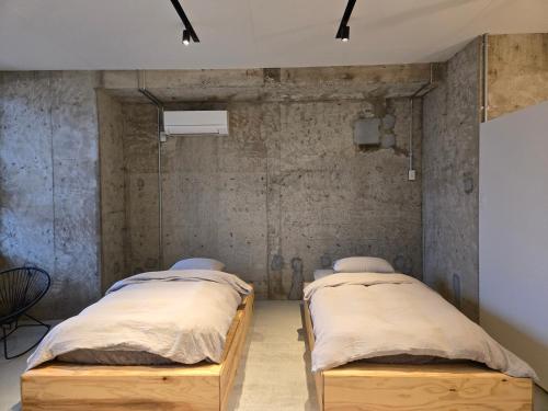 two beds in a room with concrete walls at 三笠館Mikasakan 別館 in Kinokawa