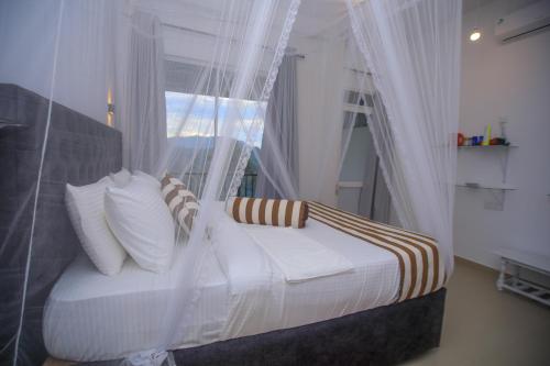 a bedroom with a bed with curtains and a window at Ella Nimal Nest Inn in Ella