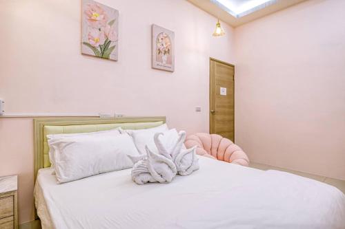 a bedroom with a white bed and a pink chair at Shijianhai B&B in Magong