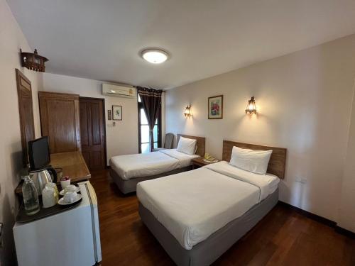 a hotel room with two beds and a television at Sripat Guesthouse SHA Extra Plus in Chiang Mai