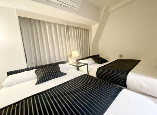 two beds sitting next to each other in a bedroom at TOKYO SPA Premier UENO in Tokyo