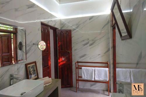 a white bathroom with a sink and a mirror at Emel's Retreat By Tropical Magnum - Luxury Boutique Villa in Anhandigoda