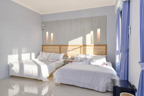 a bedroom with two beds with white sheets at Shijianhai B&B in Magong