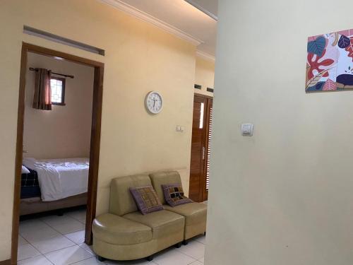 a living room with a couch and a clock on the wall at Prahu Dinar Syariah - Family in Lembang