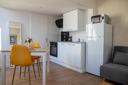 une cuisine avec une table et un réfrigérateur blanc dans l'établissement L'Amsterdam - Duplex trés calme au dernier étage, à Niort