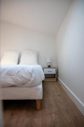 une chambre avec un lit blanc et une table de chevet dans l'établissement L'Amsterdam - Duplex trés calme au dernier étage, à Niort