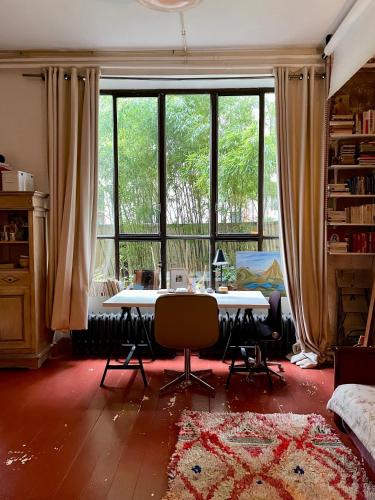 un salon avec une table et une grande fenêtre dans l'établissement Warm and cosy Loft in paris with a private outdoor, à Paris