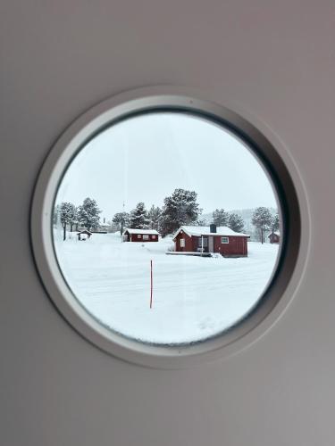 a view of a snowy field through a round window at Norwegian Wild in Vangsvik