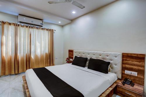 ein Schlafzimmer mit einem großen weißen Bett mit schwarzen Kissen in der Unterkunft SPOT ON Sai P Guest House in Varanasi