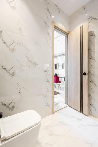 a bathroom with a white toilet and a door at Lime Tree B&B Pari Chowk in Greater Noida