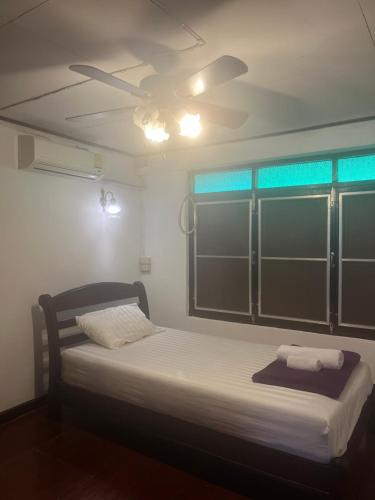 a bedroom with a bed with a ceiling fan at Tata GuestHouse in Chiang Mai