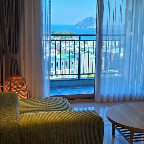 a living room with a couch and a large window at Red Hat Snail in Seogwipo