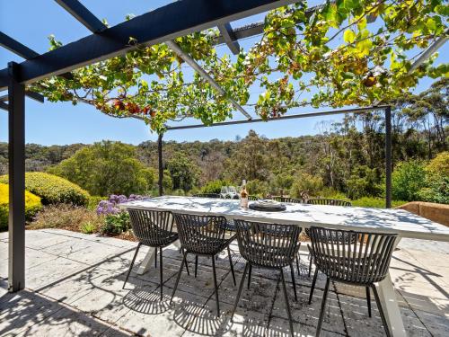 a patio with a table and chairs under a pergola at By the River - idyllic getaway in Margaret River Town