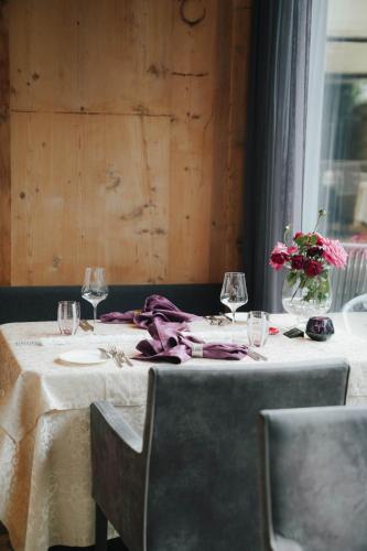 a table with wine glasses and a vase of flowers at Hotel Restaurant Kirchsteiger in Vollan