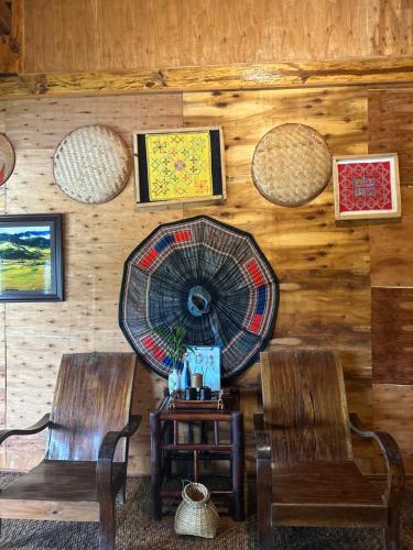 a room with two chairs and a fan on the wall at Mu Cang Chai Eco Lodge in Nam San