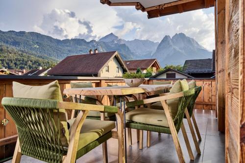 a table and chairs on a balcony with mountains at Apartment Wood&Stone Alpi in Garmisch-Partenkirchen