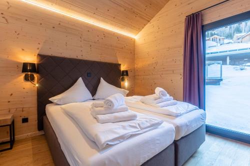 two beds in a room with a large window at Bergresort Hauser Kaibling by ALPS RESORTS in Haus im Ennstal