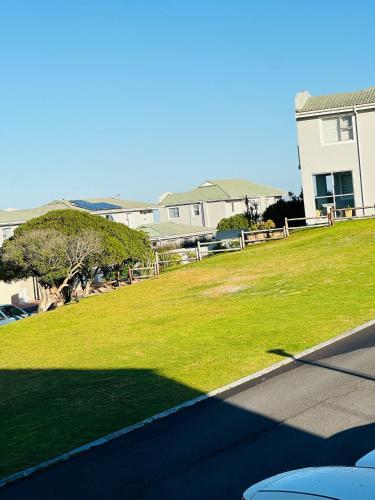 a grassy yard with a house in the background at Big Bay Beach Club in Cape Town