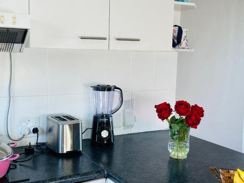 a kitchen counter with roses in a vase with a blender at Big Bay Beach Club in Cape Town