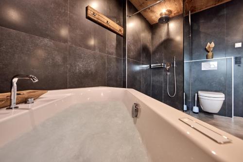 a bathroom with a bath tub and a toilet at Apartment Wood&Stone Alpi in Garmisch-Partenkirchen