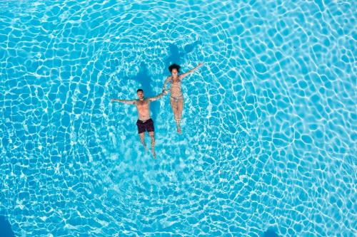 two men are swimming in a pool of water at Alianthos Garden in Plakias