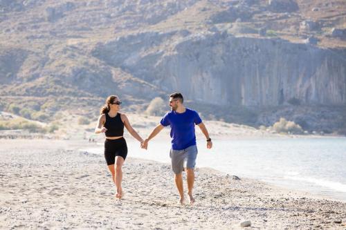 a man and a woman walking on the beach at Alianthos Garden in Plakias