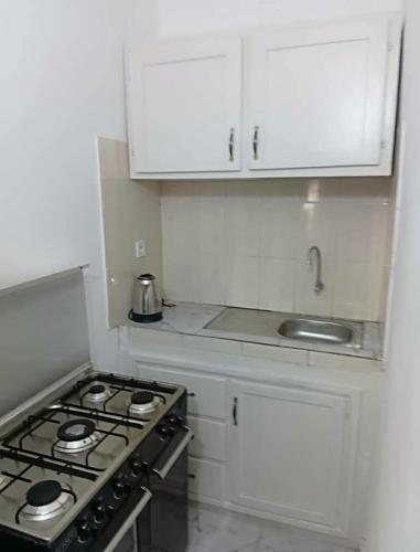 a white kitchen with a stove and white cabinets at Residence le prestige in Kribi