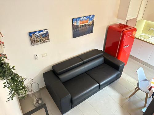 a living room with a black couch and a red refrigerator at Dimora Sant Anna in Piacenza