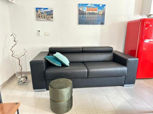 a living room with a black leather couch and blue pillows at Dimora Sant Anna in Piacenza
