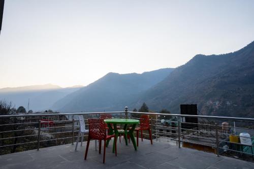a table and chairs on a balcony with mountains at Mellow- A Himalayan Home in Haripūr