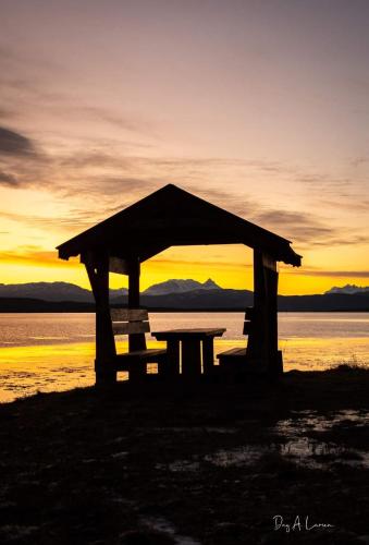 a picnic table in front of the water at sunset at Norwegian Wild in Vangsvik
