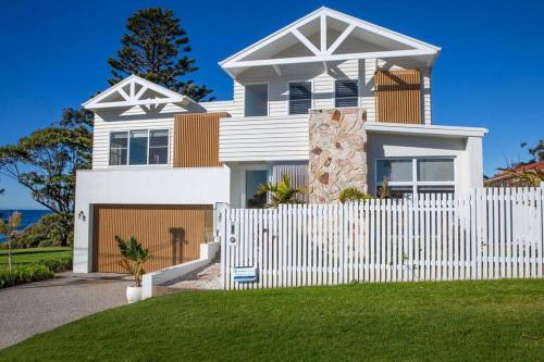 a white fence in front of a white house at LegaSea Lodge - Pet Friendly Beachfront Plunge Pool in Shellharbour
