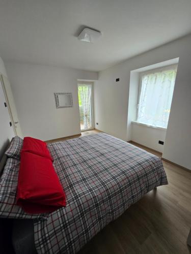a bedroom with a bed with red sheets and a window at Appartamenti a Lases in Albiano