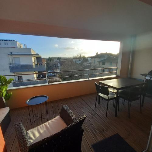 a room with a balcony with a table and chairs at Le Barbusse LYON-T3-Garage-Terrasse-3 lits-Home Cinema in Pierre-Bénite