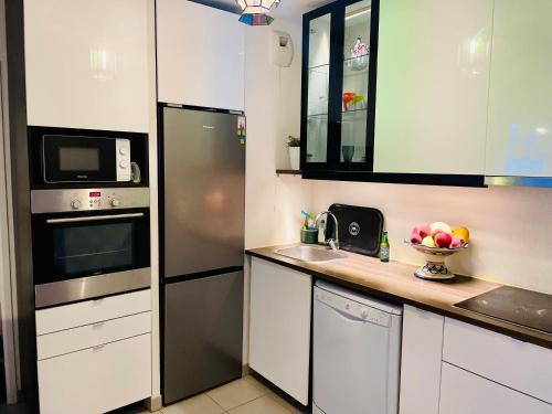 une cuisine avec des armoires blanches et un réfrigérateur en acier inoxydable dans l'établissement T3 récent avec terrasse et parking, à Marseille